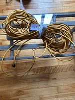 Coiled heavy duty yellow electrical cord with white extension cord wrapped around it on wooden floor.