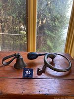 Overview of the brass bulb horn and sheep bell on wooden table by window