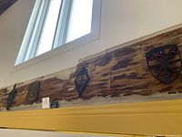 Four vintage iron trivets displayed on a wooden beam