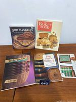 Photo showing 4 basket making books and 1 pamphlet arranged on a table, titles visible: 500 Baskets, The Basket Book, Wicker Basketry, Pine Needle Basketry, and a pamphlet with weaving patterns.