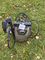 Front view of Stanley electric pressure washer with spray handle and attached hose coiled around unit, placed on grassy surface outdoors.