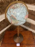 Full view of the vintage standing globe showing the wooden stand, metal base, and light blue colored globe with continents and countries.