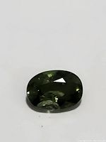 Close-up image of the oval cut green sapphire showing facets and color.