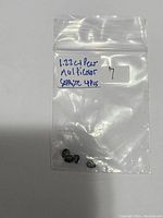 Photo of a small clear resealable plastic bag labeled with '1.22ct pear multicolor sapphire 4pcs' containing four dark pear-shaped sapphires.
