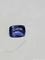 Close-up of the 1.31 carat cushion-cut blue-purple fluorite gemstone on a white background for color and clarity display.