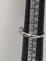 Side view of the sterling silver ring on a ring sizing stick showing the band and setting.