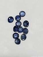 Top view showing the group of blue round cut sapphires displaying color variations and sizes within 2.5-2.8mm range.