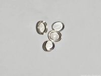 Four oval cabochon cut light morganite gemstones closely shown on a white background to highlight clarity and smooth rounded top.