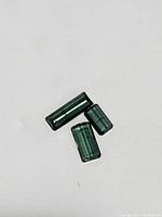 Three loose Paraiba blue colored tourmaline gemstones shown on a plain background, highlighting their emerald cuts and vibrant blue-green color.