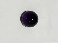 Close-up image showing the polished round cabochon purple amethyst with smooth dome surface and deep purple color.