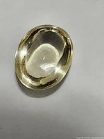 Oval cabochon cut golden citrine gemstone shown from an angled view with light reflection on the polished surface.