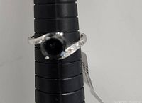 Front angle of the ring showing the black diamond center and white diamond accents.