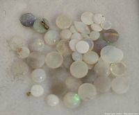 Loose genuine Australian opal stones of various sizes and colors shown in close-up on a white surface.
