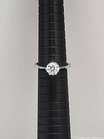 Front view of 925 sterling silver ring with clear round gemstone set in prong setting, shown on black ring sizer.