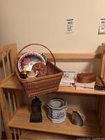 Woven basket with greeting cards, wooden trinket boxes, ceramic planter, metal owl bank, and other items on wooden shelves