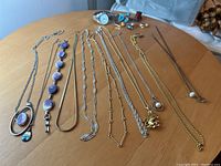 Overview of entire lot including watch, rings, necklaces and hat pins on wooden surface