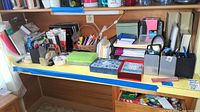 Wide view of all office supplies spread across a desk, including pens, notebooks, folders, and boxes with tape and glue sticks.