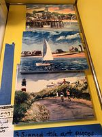 Photo showing all three ceramic tiles stacked, featuring coastal and harbor scenes, each signed by N.E. Kennedy.