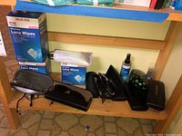 Overall view of the sunglasses, glasses cases, and boxes of lens wipes on a wooden shelf.