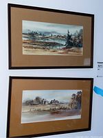 Photo of two framed watercolor paintings hanging on a wall, showing the overall lot contents as a set of two artworks.
