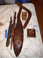 Overview of five wooden carvings, ceramic cup, and inlaid box on mattress
