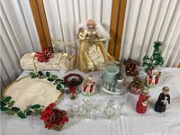 Full lot of Christmas decorations including gold angel tree topper, yule log decoration, felt holly garland, various figurines, candles, and small holiday accents.