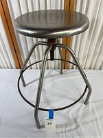 Full view of the metal work stool showing seat, frame, and legs.