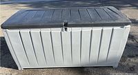 Front view of the Keter outdoor plastic deck/storage box, showing the rectangular shape, grey sides and black lid.
