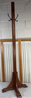 Full view of the tall, solid wood four sided coat rack showing its hooks and form.