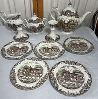 Full display of the set including teapot, sugar bowl, creamer, 5 plates and 2 candlesticks on table