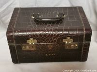 Closed antique briefcase with dark brown faux crocodile leather and brass locks with initials T.Y.D.