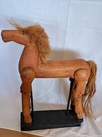 Side view of wooden horse model showing full body profile, base, and mane