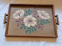 Top view showing floral cross-stitch design within the carved wooden tray with two handles.