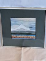 Framed fabric landscape artwork showing a mountain peak with reeds and water, the artwork measures approximately 7 x 6.5 inches.