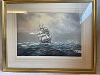 Full view of framed limited edition print showing a tall ship on the ocean with a cloudy sky, framed in gold-tone frame with white mat