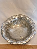 Top view showing ornate leaf and floral pattern embossed around inner sides and rim of the cast aluminum bowl.