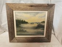 Full view of the oil painting framed in rustic wood, showing the lake landscape scene with trees and water under a cloudy sky.