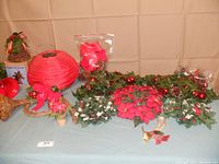 Photo of assorted Christmas greenery and decorations including garlands, candle rings, and hanging ornaments laid out on a table.