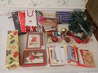 Table display of all items showing gift bags, boxed cards, loose cards, ornaments, and string lights with some focus on wine gift bags and holiday designs