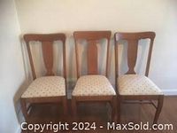 Three oak chairs arranged side-by-side showing varied back styles and light upholstery with small heart pattern.