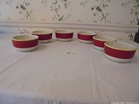 Six Royal Doulton bowls arranged on a table showing the front and sides with the red outer band and yellow trim visible.