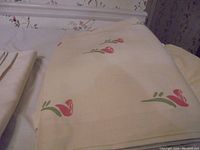 Full floral pattern sheets and pillowcases folded on table, showing light cream color with small pink and green floral print.