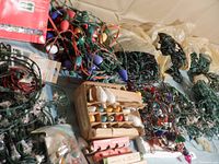 Photo showing bundles of vintage string Christmas lights with green wiring and several boxes containing replacement bulbs in cardboard packaging.