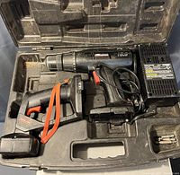 Open view of the carrying case showing cordless drill, reciprocating saw, charger, batteries, and drill bits inside