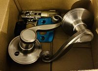 Photo of a silver scroll-door handle set with two matching handles and lock mechanism in a box.