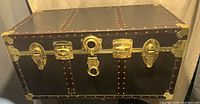 Front side of the vintage steamer trunk showing brass hardware and riveted edges