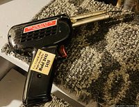 Photo of Model D440 welding tool resting on a textured mat, showing model information and price tag.