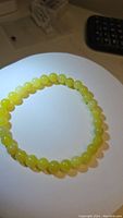 Photo showing the circular lemon jade bead bracelet on a white background, beads approx 6mm, yellow translucent color.