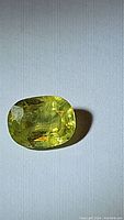 Close-up photo of 1.55ct cushion cut natural African sphene gemstone showing color and internal features under light.
