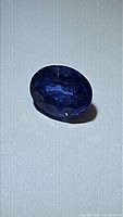 Close-up image of natural blue sapphire gemstone showing oval cut, color, and clarity characteristics.